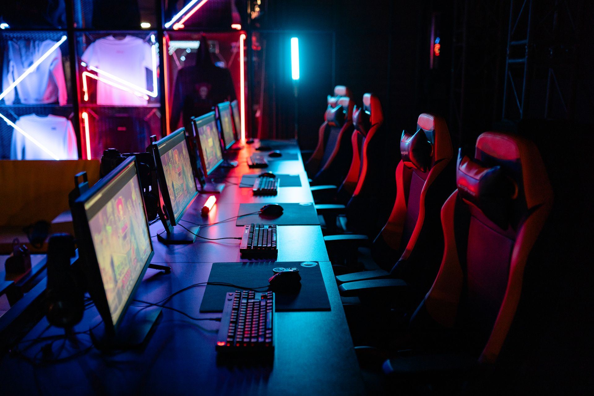 Rows of RGB-lit gaming PCs and chairs inside a cyber café
