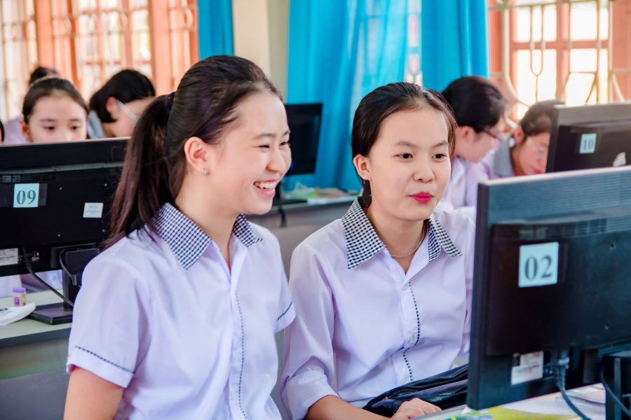 Two students smiling at a shared computer terminal